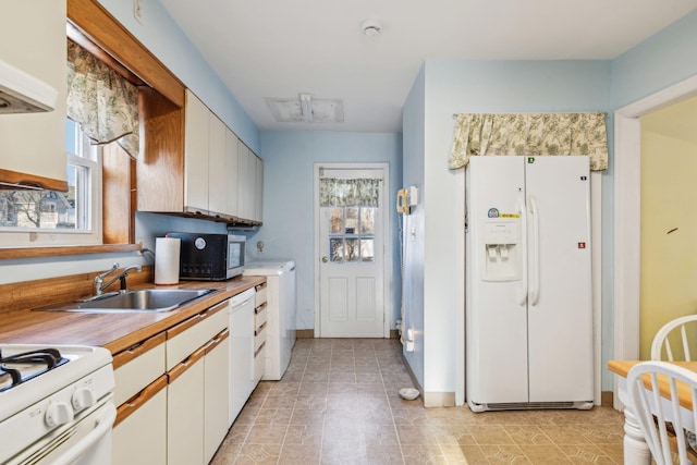 kitchen with white appliances, washer / clothes dryer, a wealth of natural light, and a sink