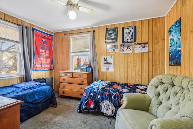 carpeted bedroom with a ceiling fan and wood walls