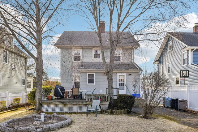 back of property with roof with shingles, fence, a chimney, and a wooden deck