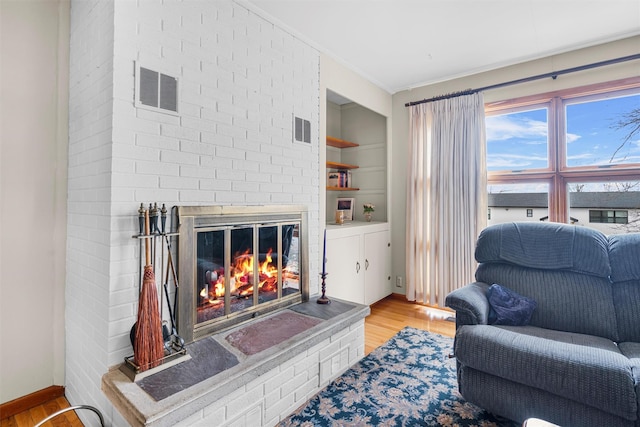 living room featuring light wood-style floors, built in shelves, and visible vents