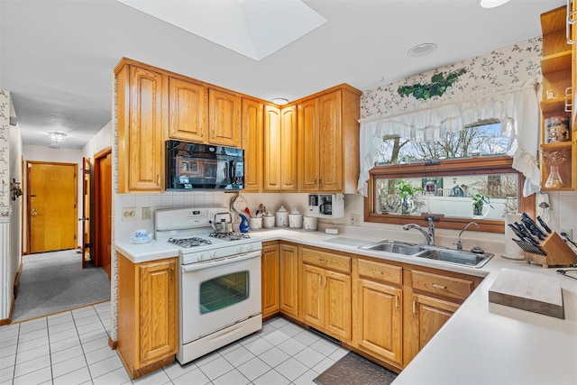 kitchen featuring white gas range, light countertops, light tile patterned flooring, a sink, and black microwave