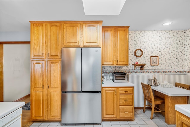 kitchen with light tile patterned floors, light countertops, freestanding refrigerator, dishwasher, and wallpapered walls