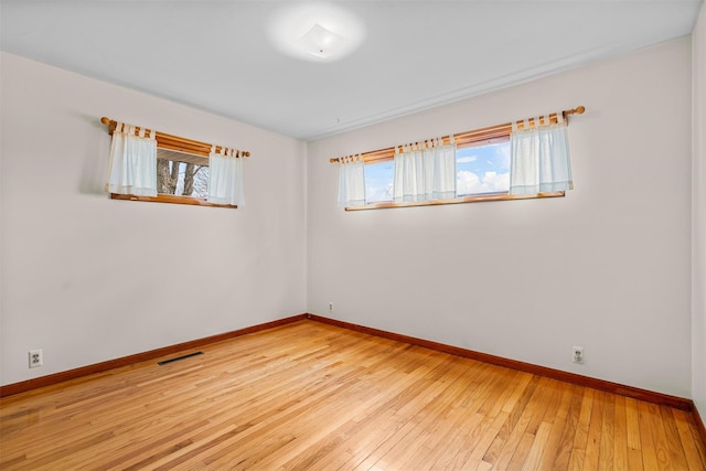 empty room with baseboards, visible vents, and a wealth of natural light