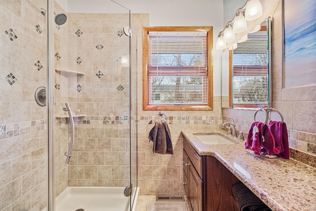 bathroom with visible vents, a shower stall, and vanity