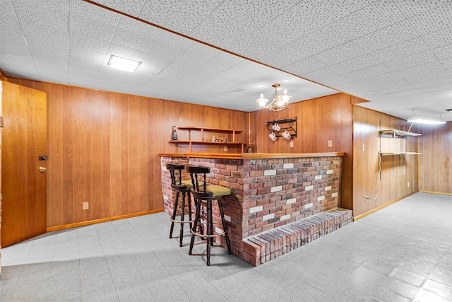 bar with baseboards, wooden walls, a dry bar, and tile patterned floors