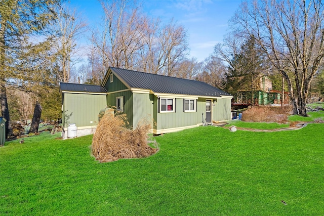 view of home's exterior with metal roof, an outbuilding, and a lawn