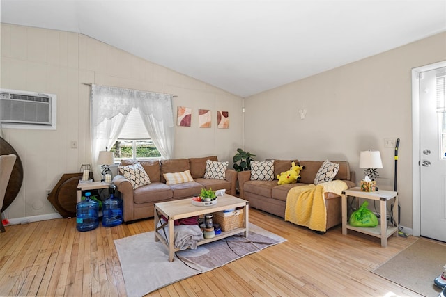 living area featuring baseboards, hardwood / wood-style flooring, a wall unit AC, and vaulted ceiling