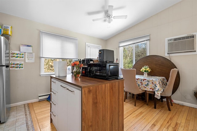 kitchen featuring lofted ceiling, light wood-style flooring, butcher block countertops, a wall mounted air conditioner, and black microwave