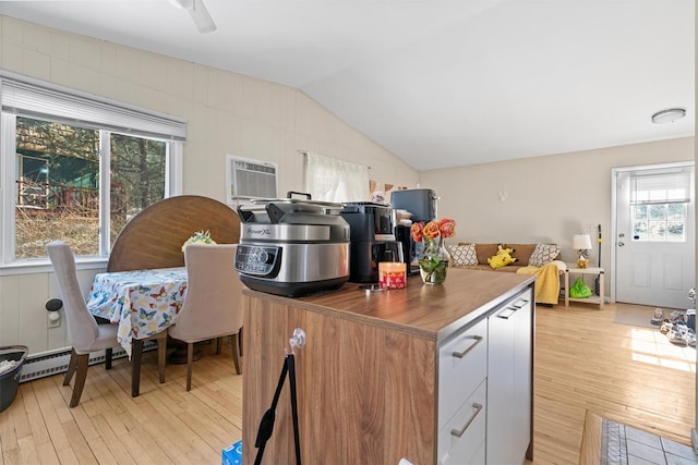 kitchen featuring lofted ceiling, dark countertops, light wood-type flooring, and a wall mounted air conditioner