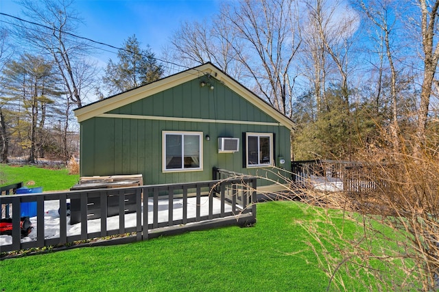 back of property with an AC wall unit and a lawn