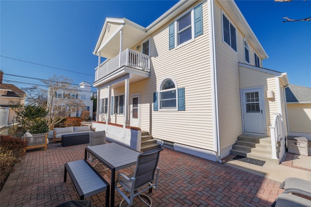 rear view of property with entry steps, a patio, an outdoor hangout area, and a balcony