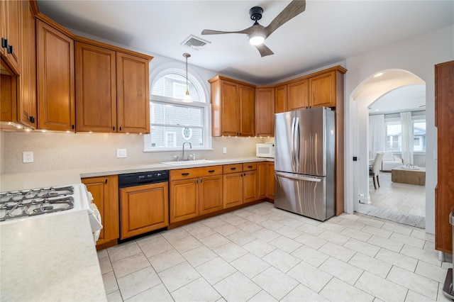 kitchen with brown cabinets, light countertops, visible vents, a sink, and white appliances