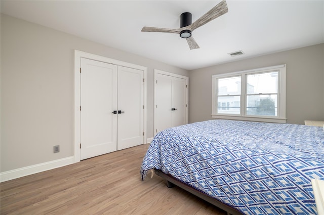 bedroom with multiple closets, visible vents, ceiling fan, light wood-type flooring, and baseboards