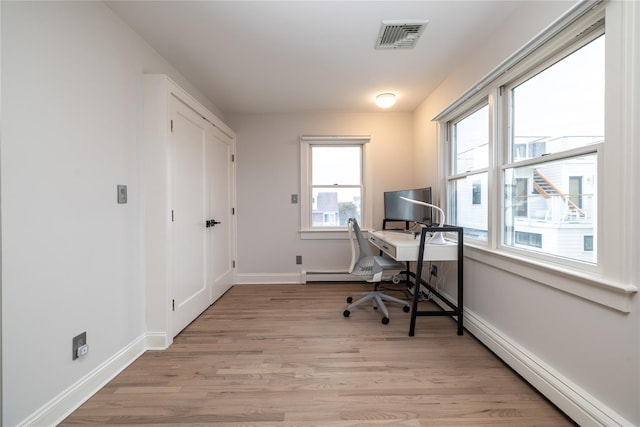 office space with baseboard heating, visible vents, light wood-style flooring, and baseboards