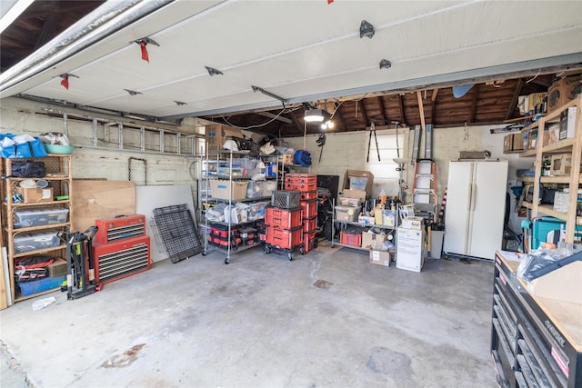 garage featuring a garage door opener, a workshop area, and freestanding refrigerator