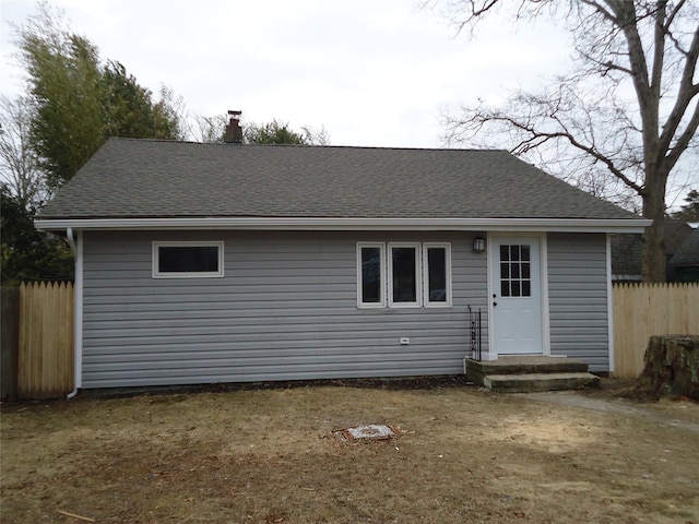 back of property featuring a shingled roof and fence