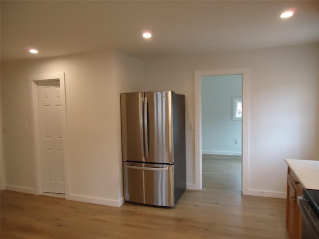 kitchen featuring baseboards, range, light wood-style flooring, freestanding refrigerator, and recessed lighting