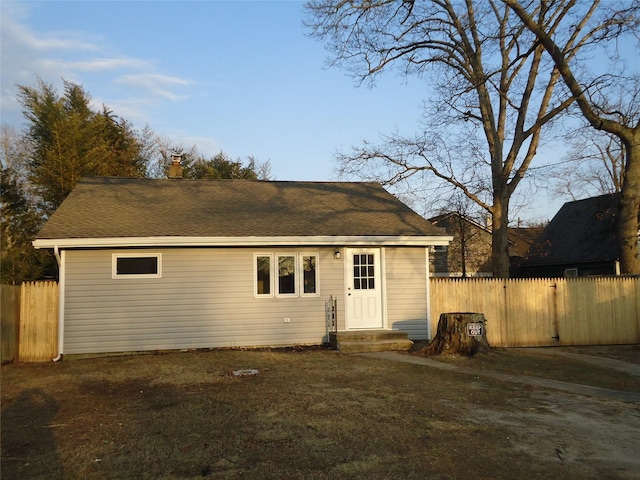 view of front facade featuring a shingled roof, fence, and a chimney