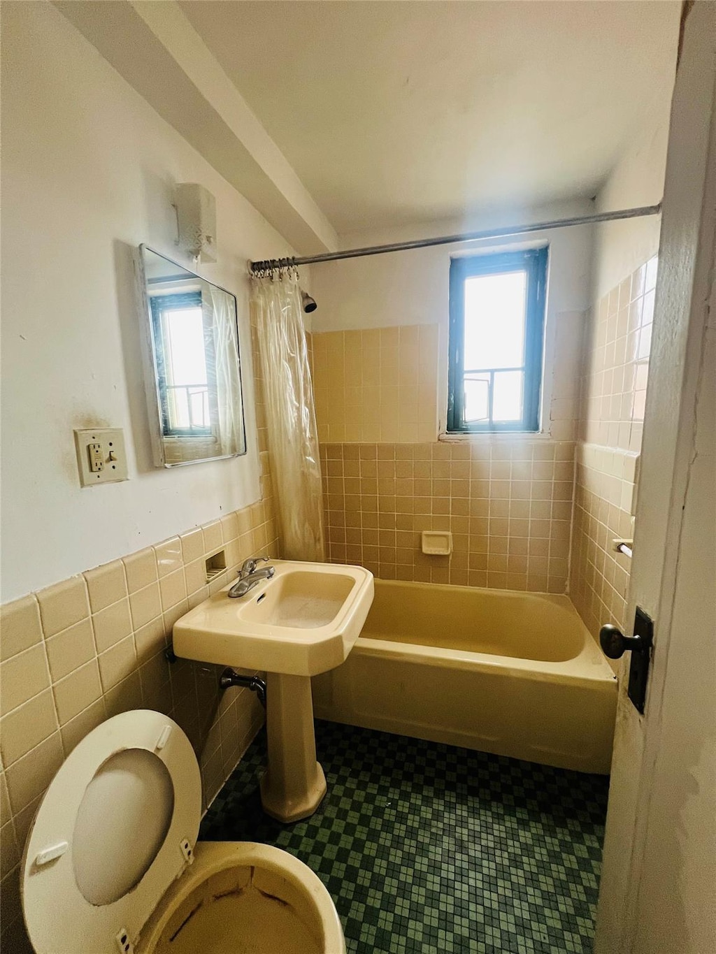 bathroom with shower / tub combo, plenty of natural light, tile walls, and toilet