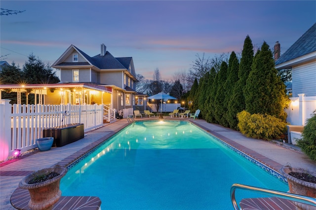 pool at dusk with a fenced in pool, a patio area, and fence