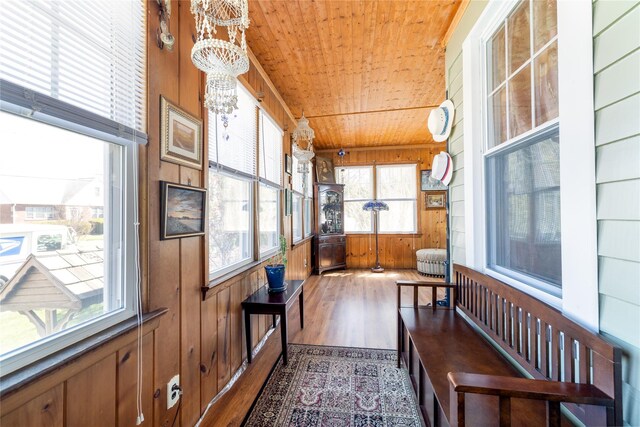 sunroom / solarium with wood ceiling and an inviting chandelier