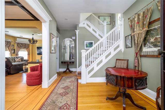 stairway with a notable chandelier, decorative columns, baseboards, and wood finished floors