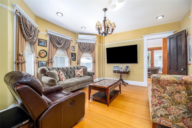 living room featuring baseboards, a wall mounted air conditioner, an inviting chandelier, light wood-type flooring, and recessed lighting