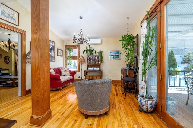 sitting room featuring light wood-style floors, baseboards, a chandelier, and a wall mounted AC