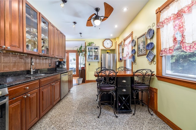 kitchen featuring stainless steel appliances, a sink, decorative backsplash, and baseboards