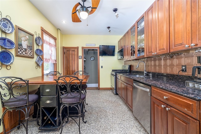 kitchen featuring tasteful backsplash, baseboards, appliances with stainless steel finishes, dark stone countertops, and a sink