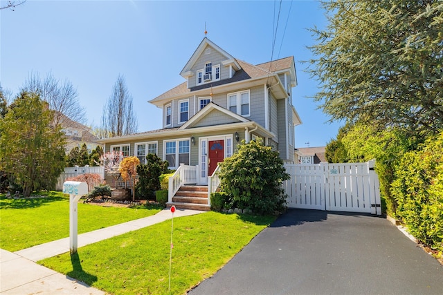 american foursquare style home featuring a gate, fence, and a front lawn