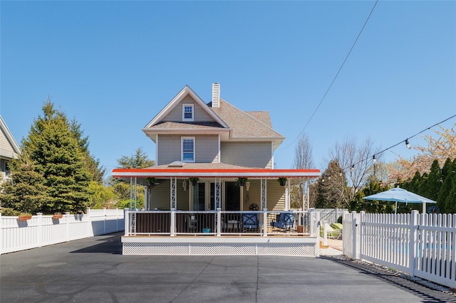 view of front of property with a gate, a chimney, fence, and a porch