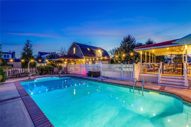 pool at dusk with a fenced in pool, fence, and a wooden deck