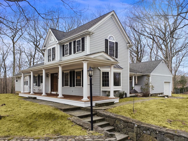 view of front facade with a porch, a front yard, and roof with shingles