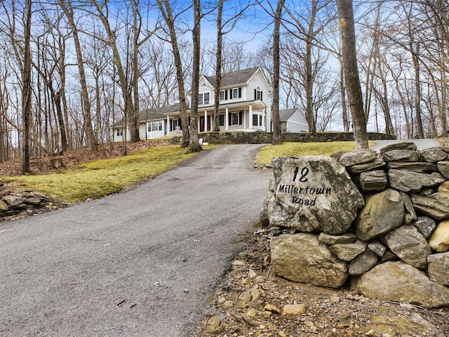 view of front facade with aphalt driveway, covered porch, and a front yard