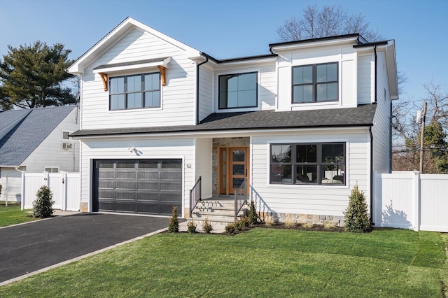 view of front of home with driveway, a shingled roof, an attached garage, fence, and a front yard