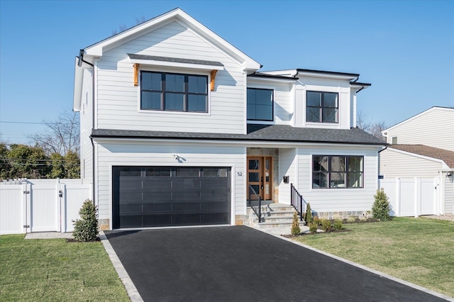 view of front of house featuring an attached garage, a gate, fence, and a front lawn