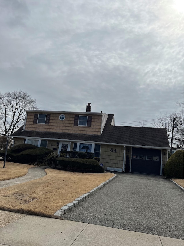 view of front of property featuring a garage, a chimney, and aphalt driveway