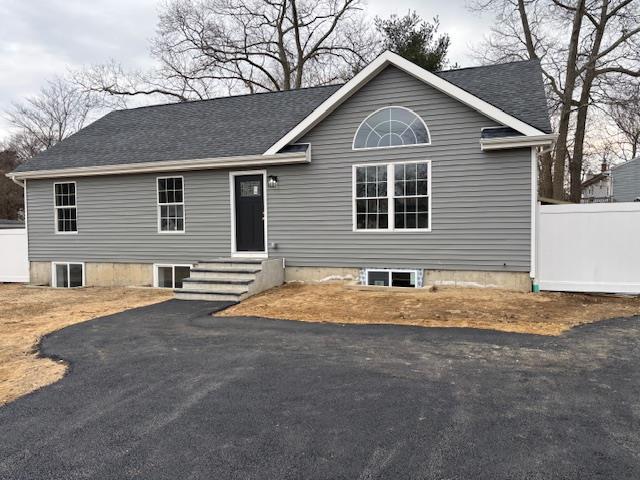 view of front of property featuring entry steps, a shingled roof, and fence