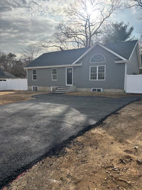 view of front facade featuring aphalt driveway, entry steps, central AC, and fence