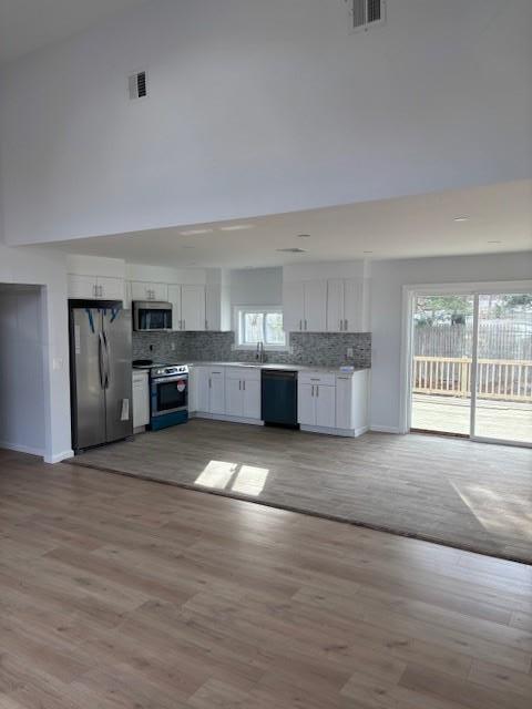 kitchen featuring appliances with stainless steel finishes, white cabinets, visible vents, and tasteful backsplash