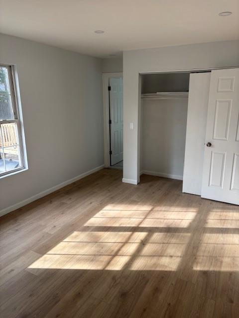 unfurnished bedroom with a closet, baseboards, and wood finished floors