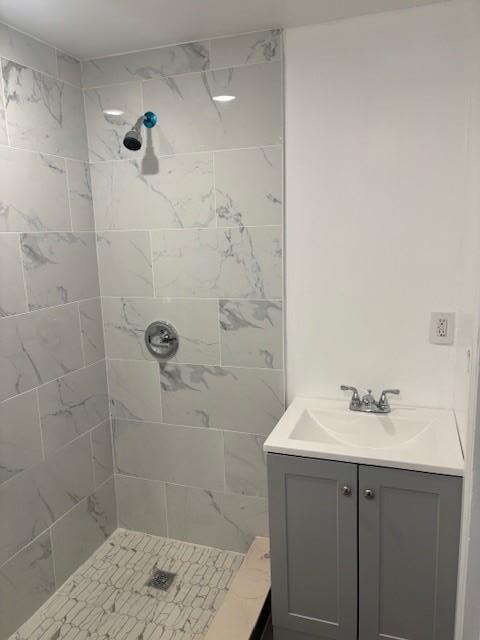 full bath featuring a tile shower and vanity