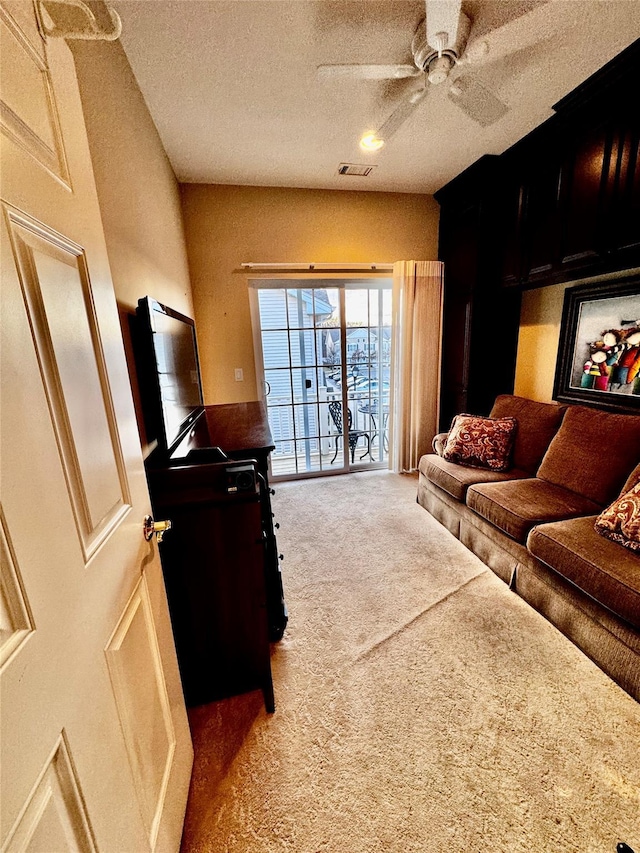 carpeted living area featuring ceiling fan, visible vents, and a textured ceiling