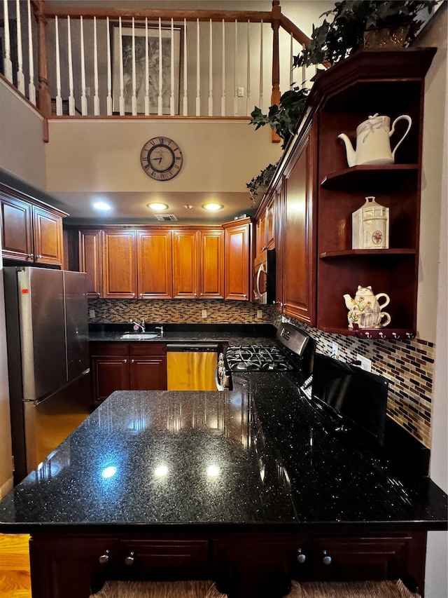 kitchen with appliances with stainless steel finishes, a towering ceiling, dark stone countertops, and open shelves