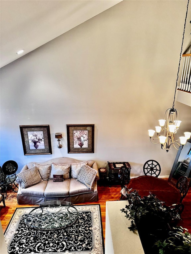living area with high vaulted ceiling, a chandelier, and wood finished floors