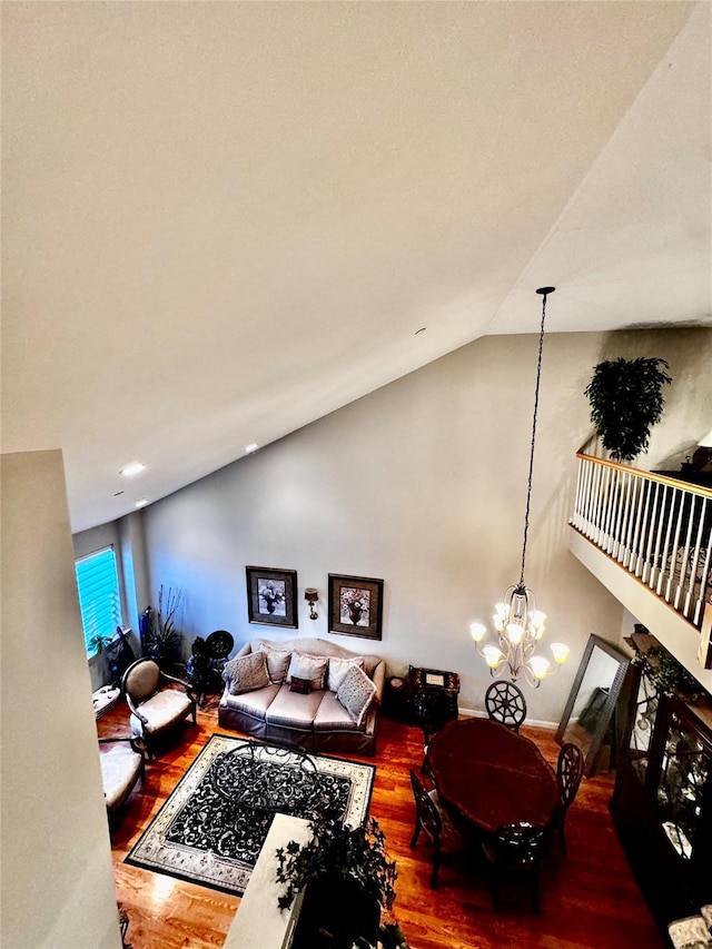 living area with high vaulted ceiling, wood finished floors, and a notable chandelier