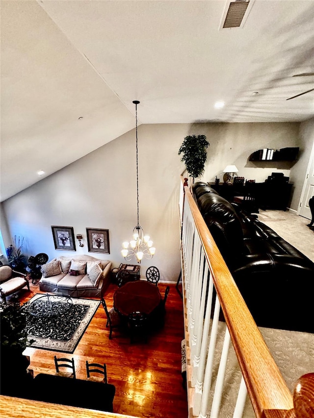 living area with lofted ceiling, an inviting chandelier, visible vents, and wood finished floors
