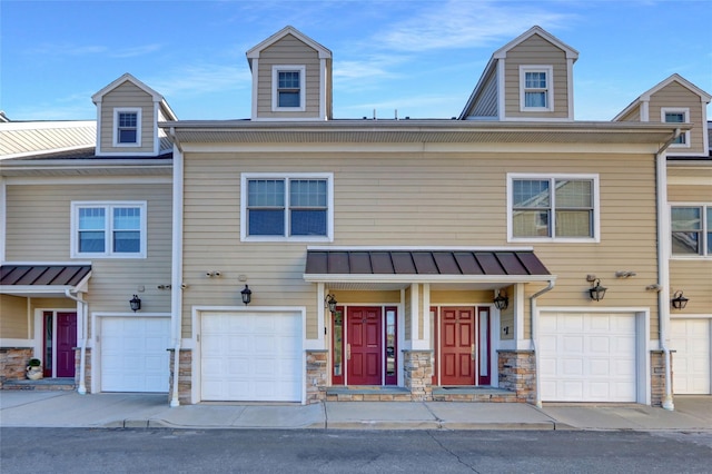 multi unit property with a garage, stone siding, a standing seam roof, and metal roof