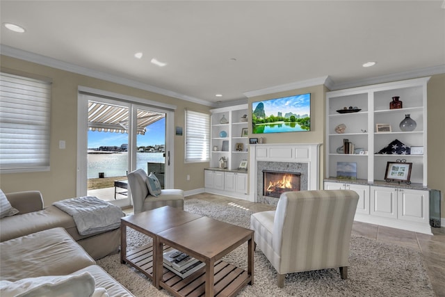 living room featuring built in shelves, ornamental molding, a high end fireplace, and recessed lighting